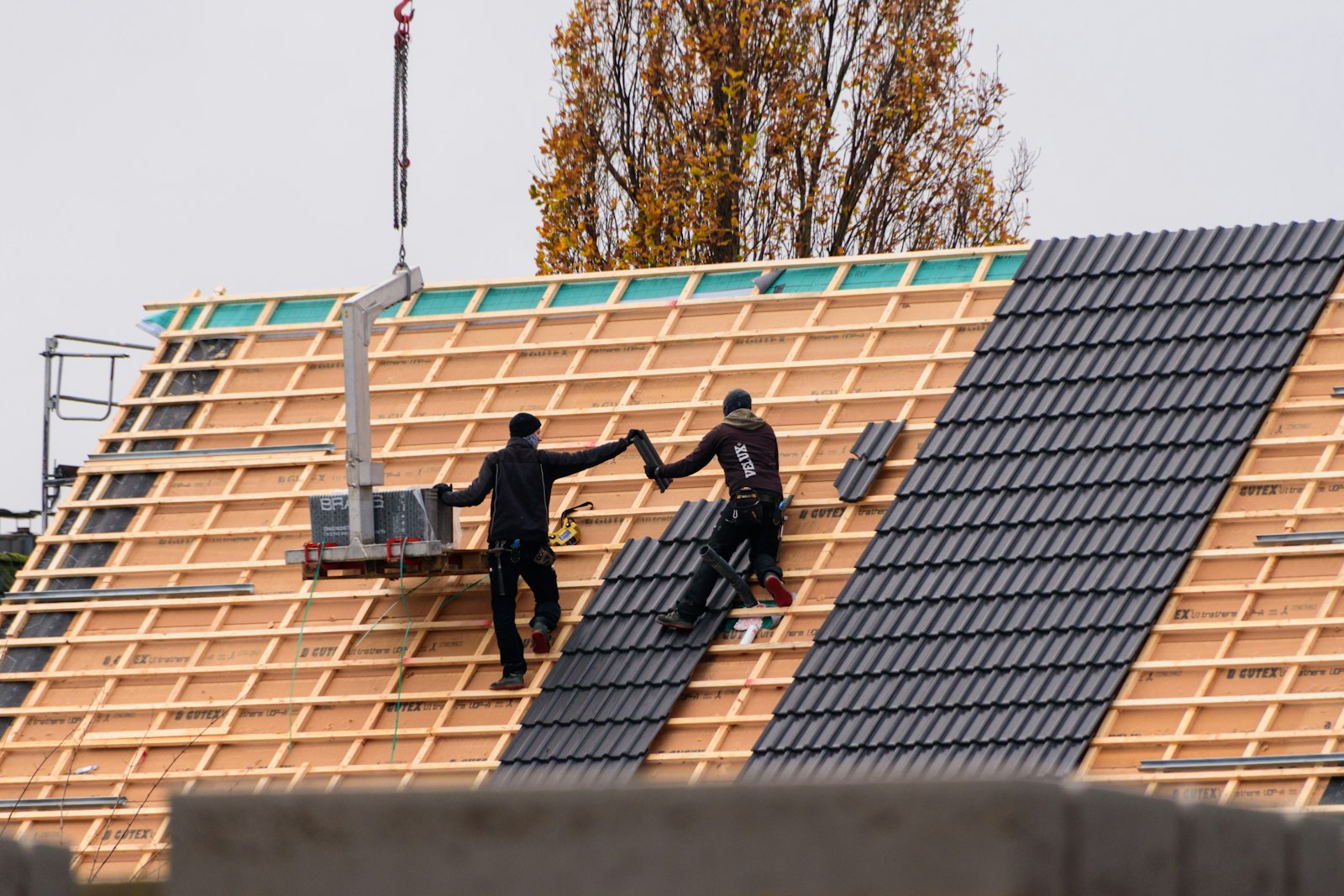 Couvreurs posant des tuiles sur une toiture neuve