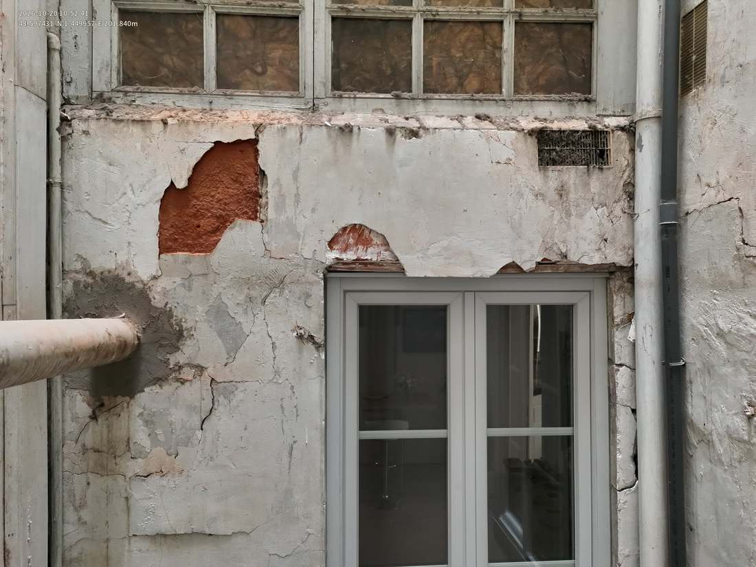 Façade SE du puits de lumière, enduit tombé autour d'une fenêtre