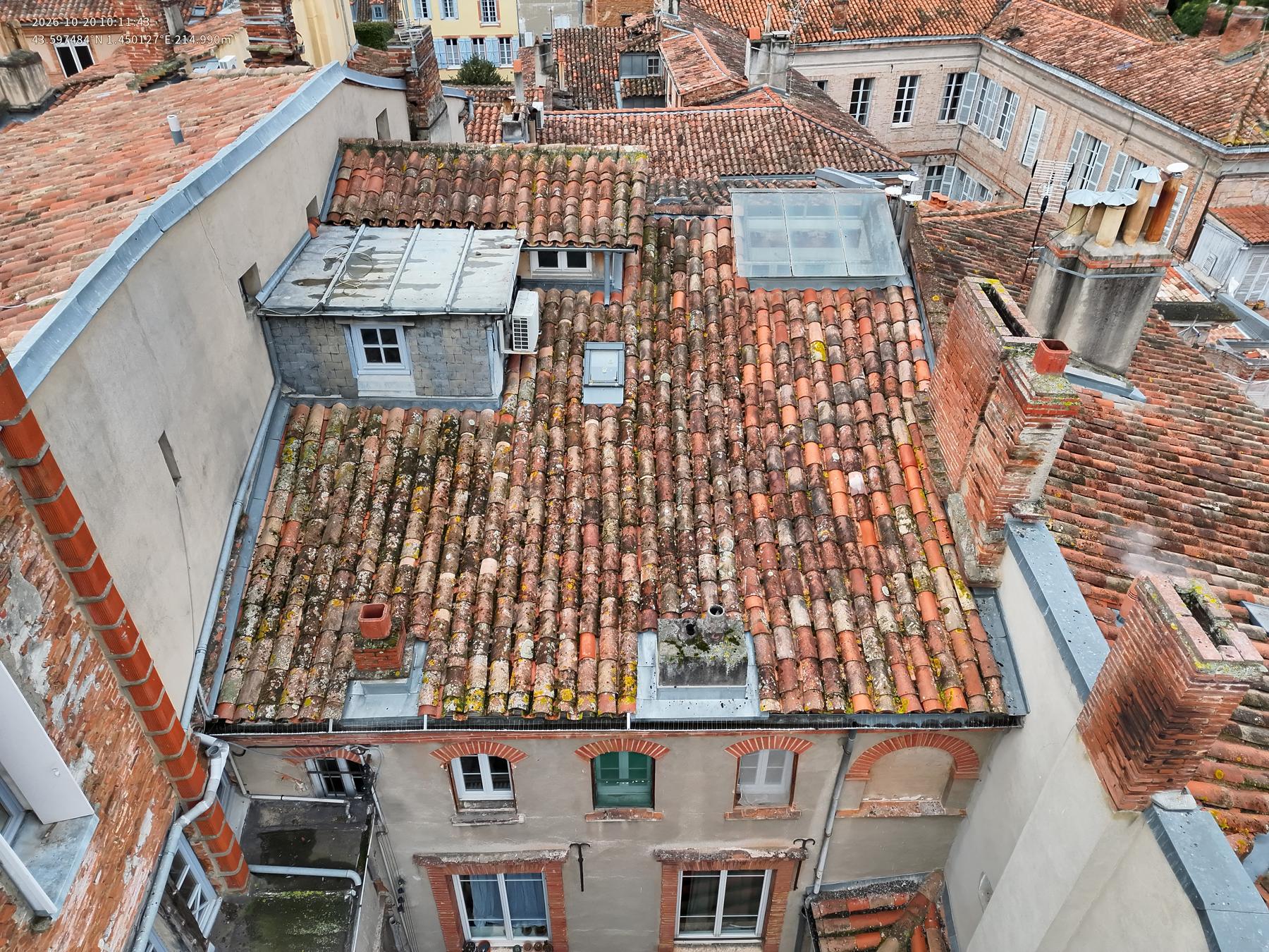 Vue aérienne d'une toiture en tuiles canal avec lucarnes et cheminées